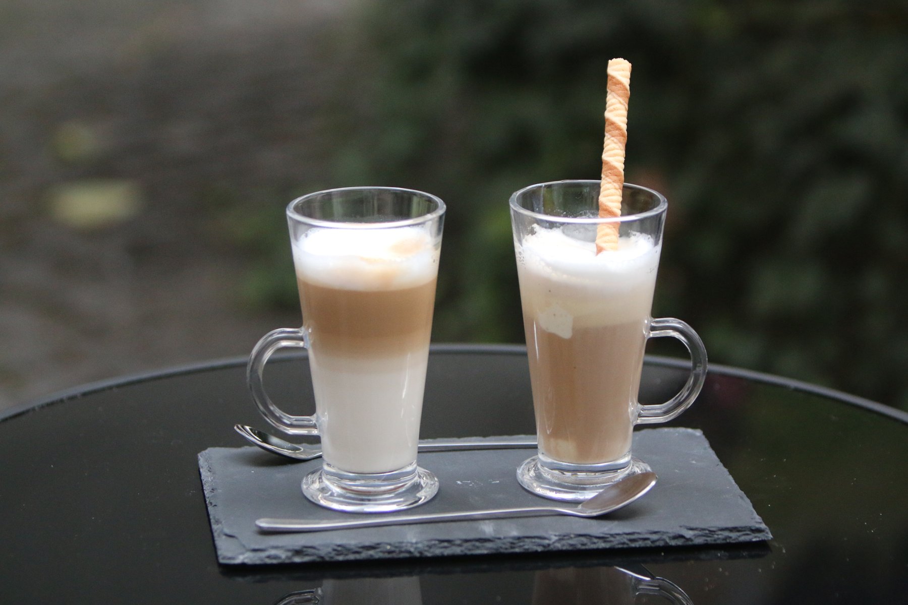 Két latte macchiato ostyarúddal az udvari asztalon